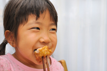 鶏のから揚げを美味しそうに食べる女の子