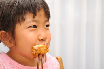 鶏のから揚げを美味しそうに食べる女の子