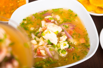 Little pieces of fish used for ecuadorian ceviche, red onions and coriander on a white dish