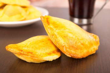 Fried filled empanadas on a table, behind delicious coffee