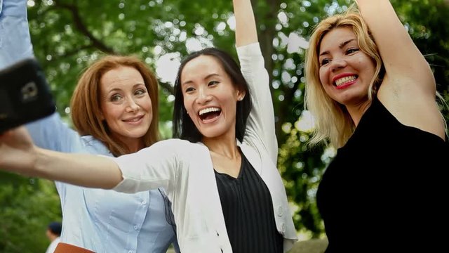 Three cheerful friends taking a selfie outdoors.