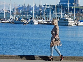 Young Woman Walking on Sea Wall with City View. Stanly Park, Vancouver, British Columbia, Canada. 

