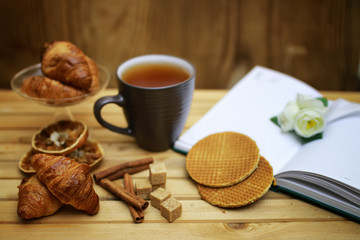 Fototapeta na wymiar cup with tea croissant book