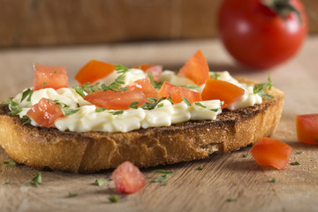 Melted cheese cream on toast with tomato and herbs