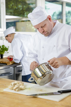 Professional chefs makes food dishes in large kitchen