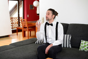 bearded man in white shirt with bow-tie drinking water
