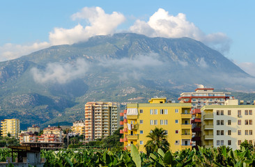 Modern Mediterranean city on the background of mountains and clouds.
