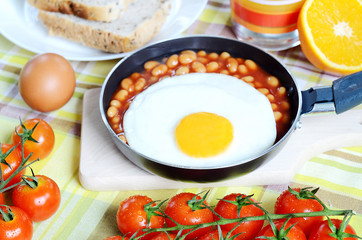Fried egg with beans, toast bread, fresh juice, tomatoes and oranges