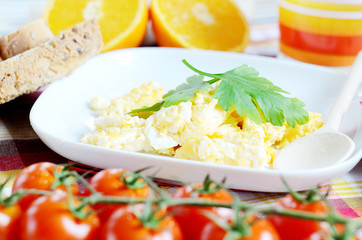 Scrambled eggs, toast bread, fresh juice, tomatoes and oranges