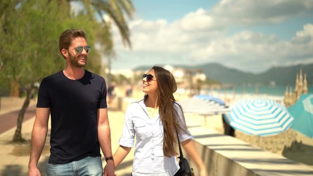 4k footage, young couple walking on boardwalk at seaside on sunny day in spring
