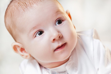 newborn baby in a beautiful white dress on a light background , portrait .