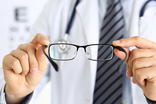 Male medicine doctor hands giving pair of black glasses