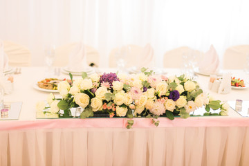 Elegantly decorated with white flowers, glasses and candles restaurant for celebrating wedding 