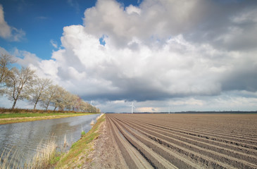 plowed potatto field and windmill turbines