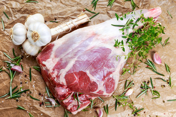 Raw lamb leg on crumpled paper background with herbs. © grinchh