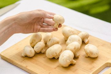 Mushrooms and Food theme: man preparing porcini mushrooms on a wooden board on a background of green grass in summer