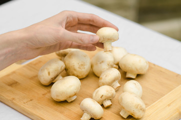 Mushrooms and Food theme: man preparing porcini mushrooms on a wooden board on a background of green grass in summer