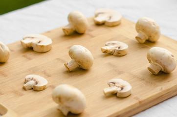 Mushrooms and Food theme: man preparing porcini mushrooms on a wooden board on a background of green grass in summer