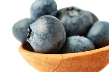 Wooden spoon filled of Bilberry or blueberry over isolated white background