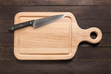 Knife and cutting board on the wooden background