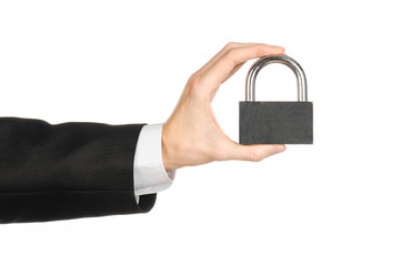 Protection and business theme: a man in a black suit holding a metal padlock isolated on a white background in studio