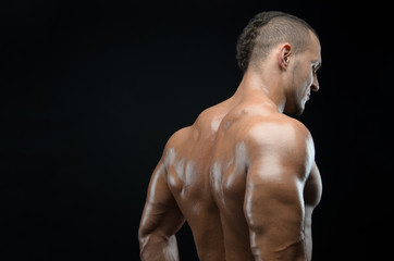 Fototapeta premium Bodybuilder and strip theme: beautiful with pumped muscles naked man posing in the studio on a dark background