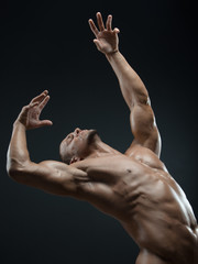 Bodybuilder and strip theme: beautiful with pumped muscles naked man posing in the studio on a dark background - 109367833