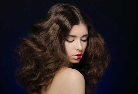 Hair and make-up topic: a very beautiful girl model with lush hair and creative make-up on blue background