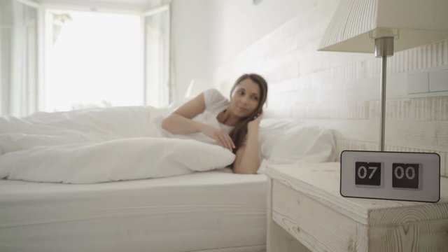 4k footage, couple sleeping in modern bedroom, alarm waking them up, focus on clock
