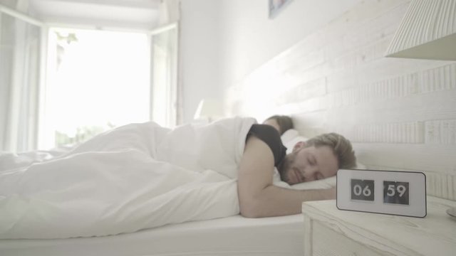 4k footage, couple sleeping, alarm ringing, man tired because of time shift
