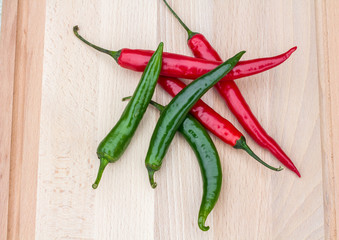 red and green chilli peppers on a chopping wooden board