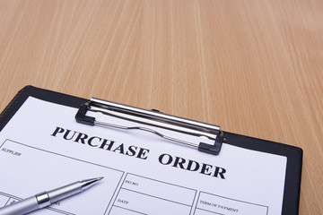 Purchase order and pen on wooden table