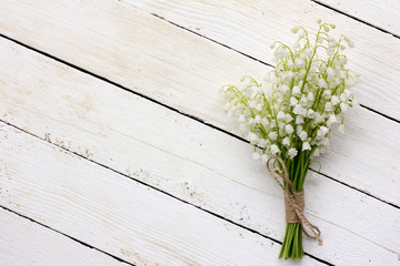 lily of the valley bouquet of white flowers tied with string on a white background barn boards. with space for posting information