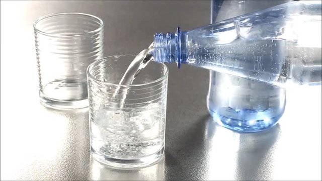 Mineralwasser aus Flasche wird eingeschenkt, Zeitlupe