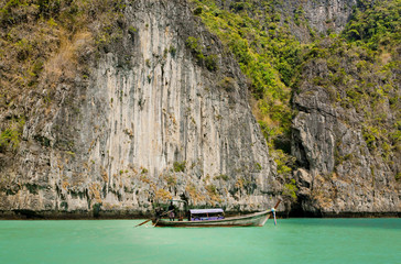Andaman Sea blue waters under karst cliffs and the fishing boat.