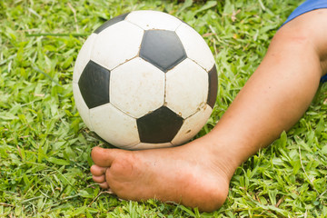 Boy play soccer in grass field.