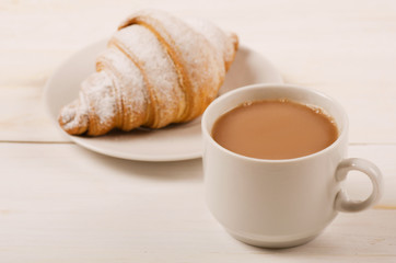 Delicious cup of coffee and croissant