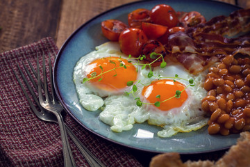 Breakfast with fried eggs, bacon, beans and cherry tomatoes  