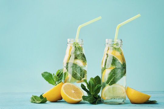 Lemonade drink of soda water, lemon and mint leaves in jar on turquoise background