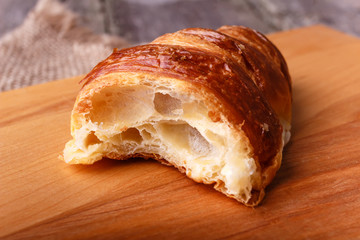 The half of fresh baked different croissant on wooden table in rustic style