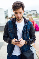 Handsome student using mobile phone in the street.