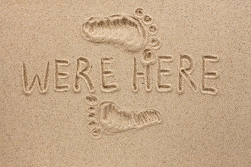 Word WERE HERE written on the sand