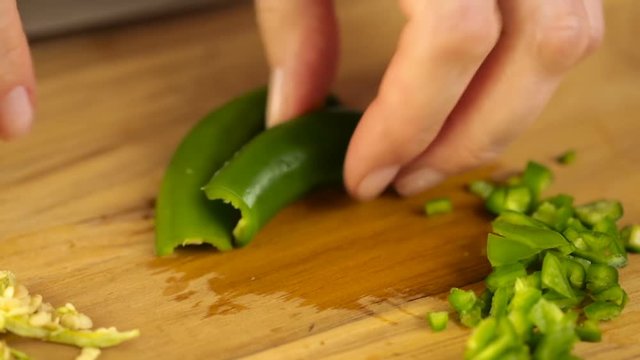 Slicing organic serrano pepper on wood cutting board