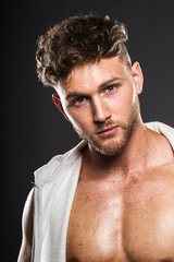 Portrait of handsome young bodybuilder , on grey