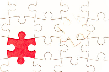 the hidden solution, still life with a white jigsaw/puzzle incomplete over a red background, the last piece is over the other one, symbol of problem solving