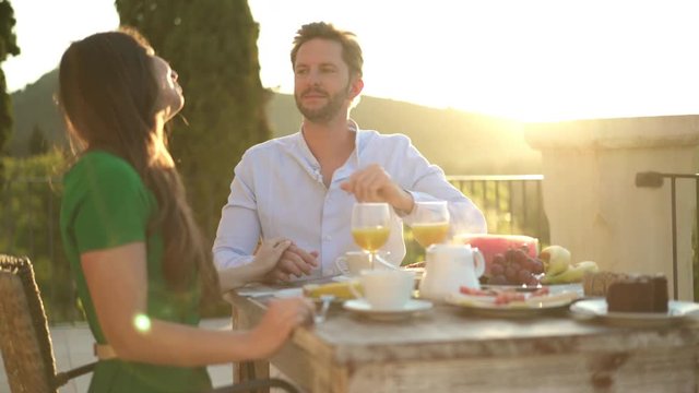 4k footage, man feeding woman with grapes during breakfast outside on veranda
