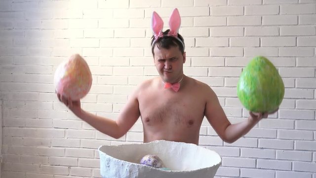 An actor dressed as the Easter bunny with big easter eggs posing at the camera in honor of the holiday