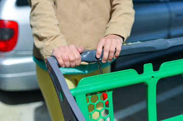 Woman with shopping cart on car parking