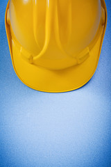 Yellow hard hat on blue surface top view construction concept