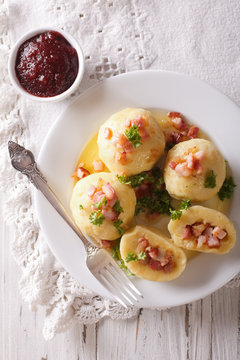 potato dumplings with bacon close-up and lingonberry sauce. vertical top view
